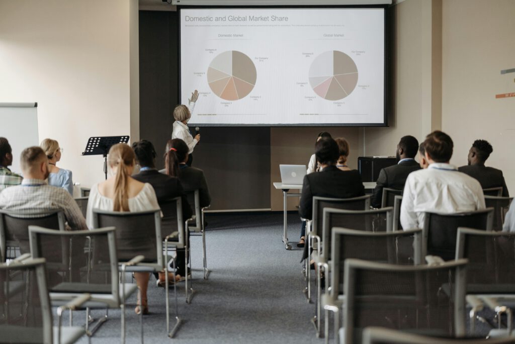 pexels photo 8761520 8761520 Business conference with diverse audience and speaker presenting market data.